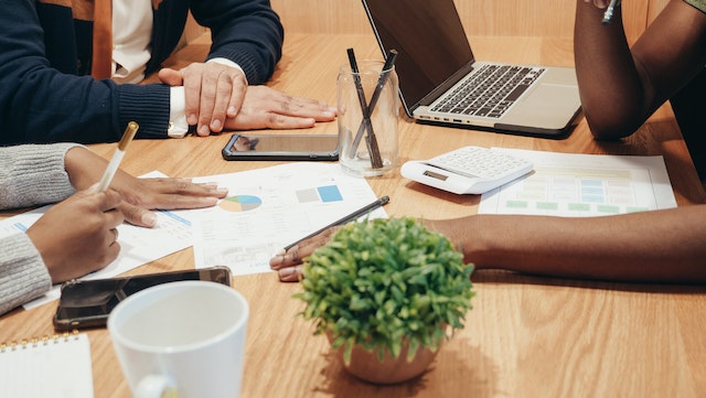 three people at a conference table looking over documents with graphs on them